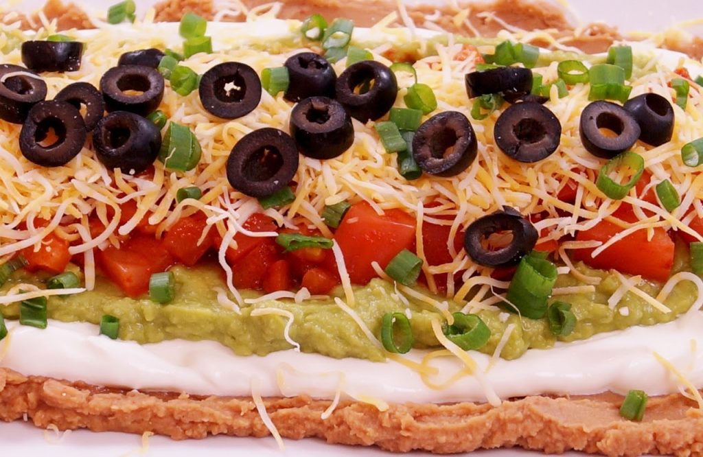 Trổ tài làm món ăn seven-layered taco dip hoàn toàn không khó! Với những lớp đầy màu sắc từ phô mai, thịt bò xé, rau cải, cà chua,... bạn sẽ tạo ra một món ăn vặt đậm chất Mexico ngon lành cỡ nào. Ảnh chụp món ăn này sẽ khiến bạn không thể không muốn thử ngay lập tức.