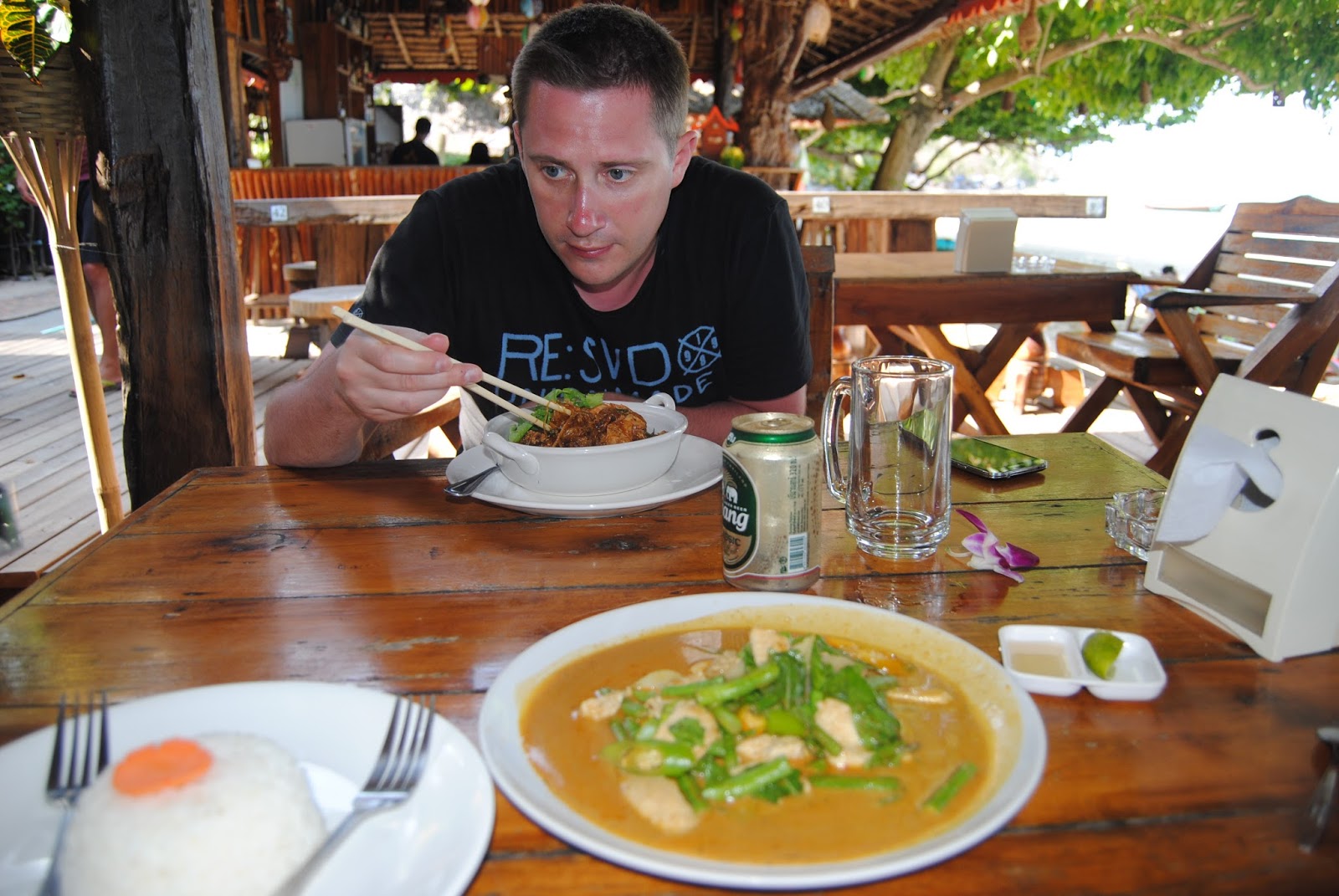 Łukasz eating green curry at a beach restaurant in Thailand